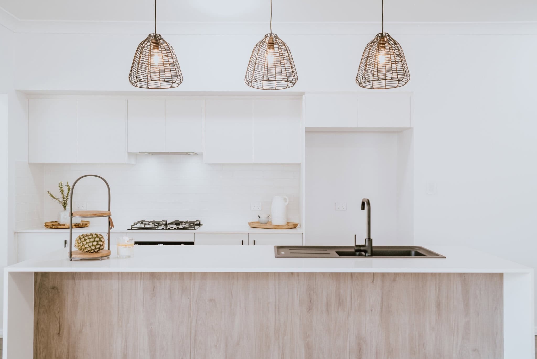 Modern white kitchen with wooden island, pendant lighting, and contemporary design | Edwards Family Homes.