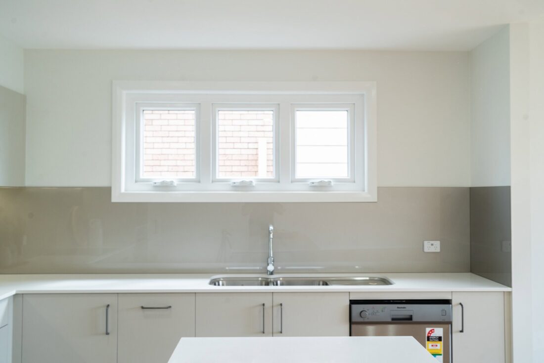 Bright modern kitchen with large window, sleek cabinetry, and built-in dishwasher, ideal for family homes.