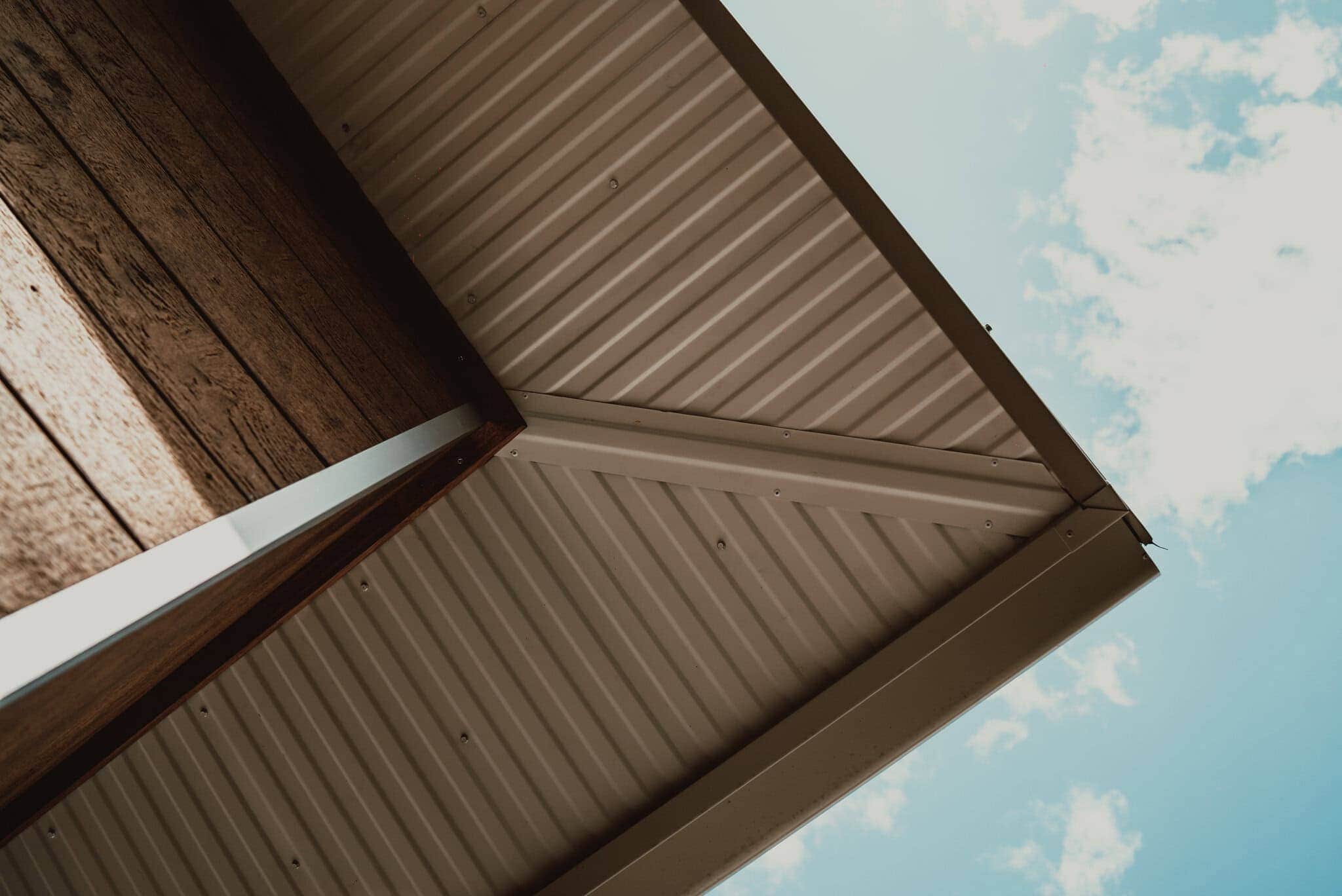 Bright modern house exterior with metal roofing and wood accents, showcasing custom home designs by Edwards Family Homes.