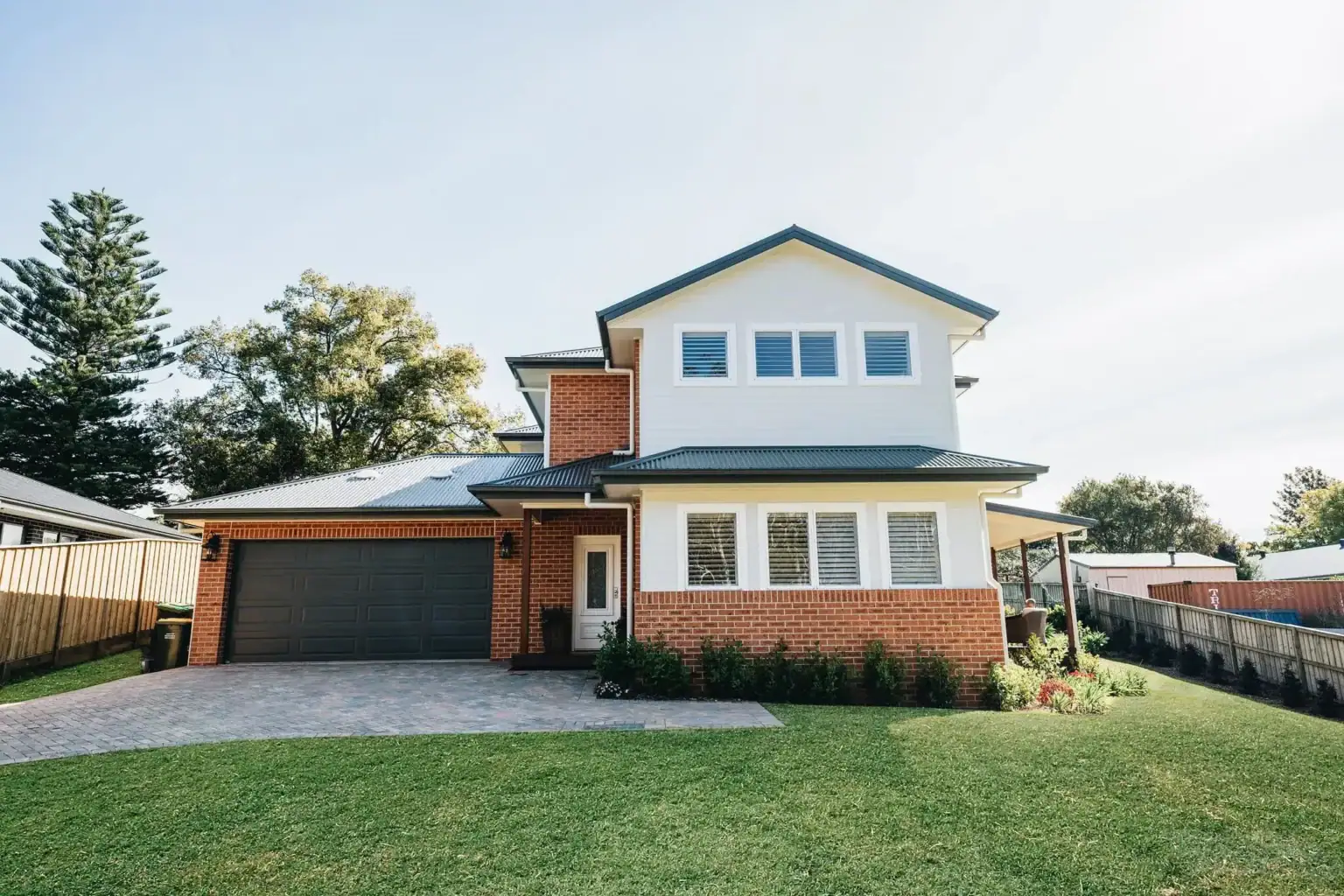 Modern two-story custom home with brick and white weatherboard exterior, landscaped garden, double garage, and large front yard.