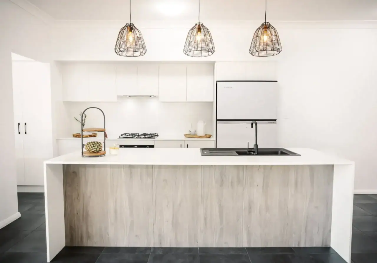 Bright modern white kitchen with island, pendant lighting, and sleek appliances – Edwards Family Homes.