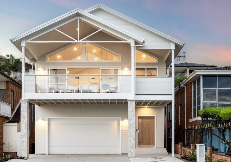 Two-storey custom home with gabled roof, white chamfer cladding and upper deck at dusk, built by Edwards Family Homes