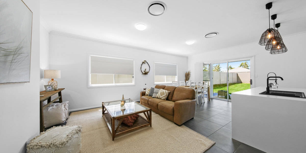Modern, spacious family home living room with natural light, stylish decor, and open-plan kitchen in Brisbane.