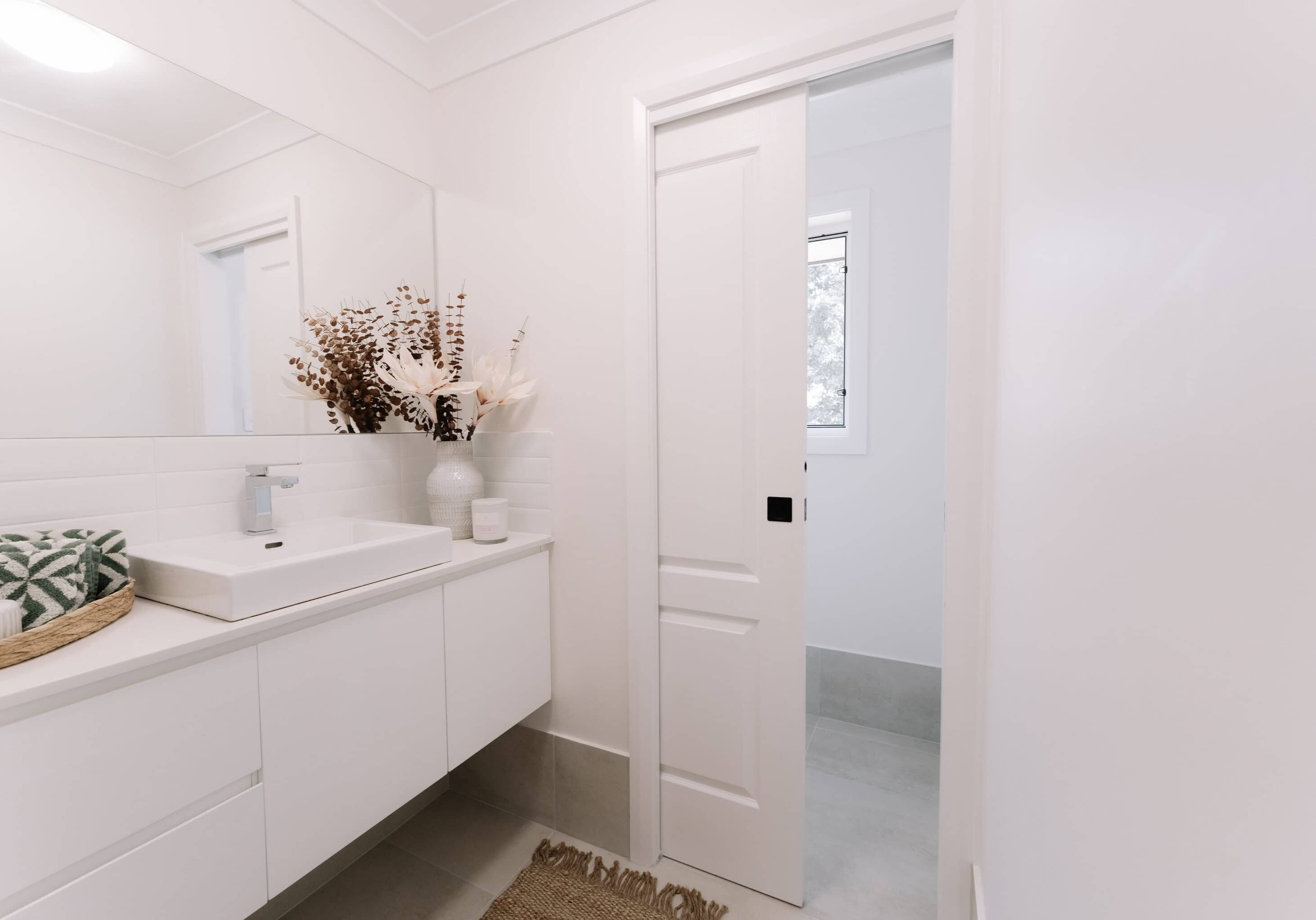 Bright modern bathroom with white cabinetry and stylish decor - Edwards Family Homes.